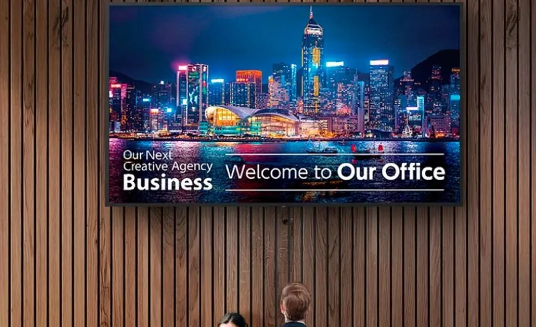 A large screen on a wooden wall welcoming visitors to an office.