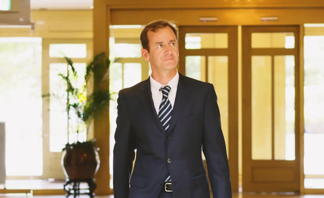 A man in a suit walking through a hotel lobby.