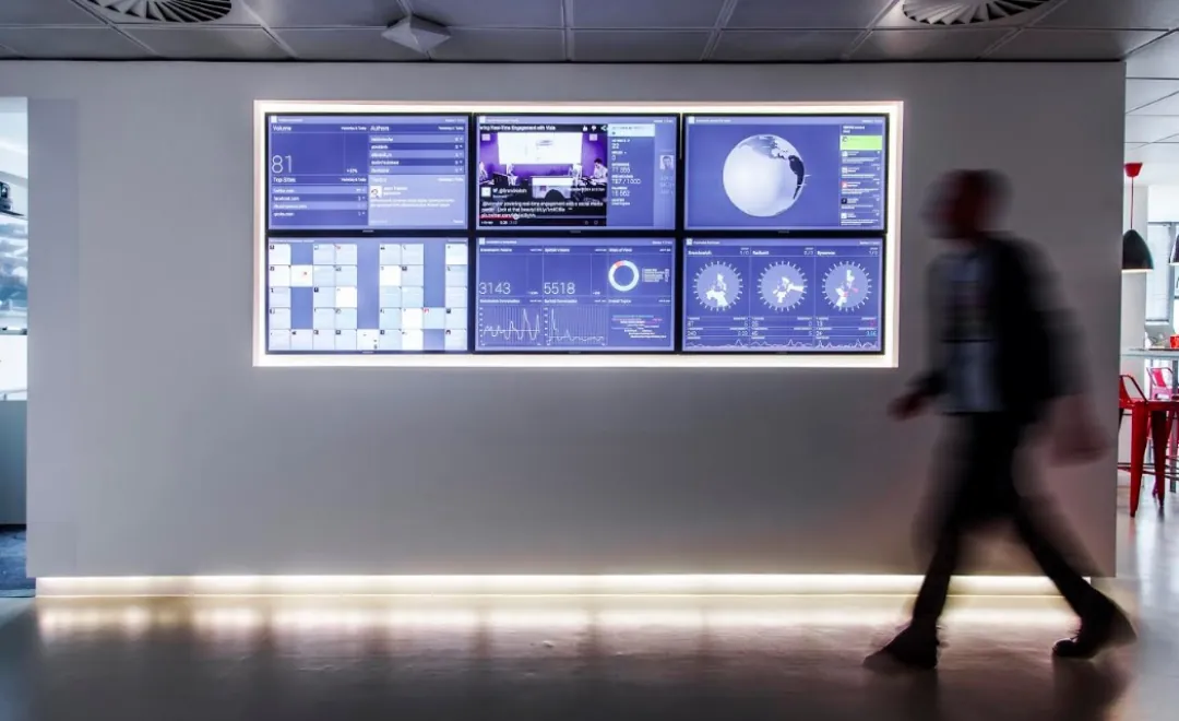 A video wall of dashboards in an office corridor.