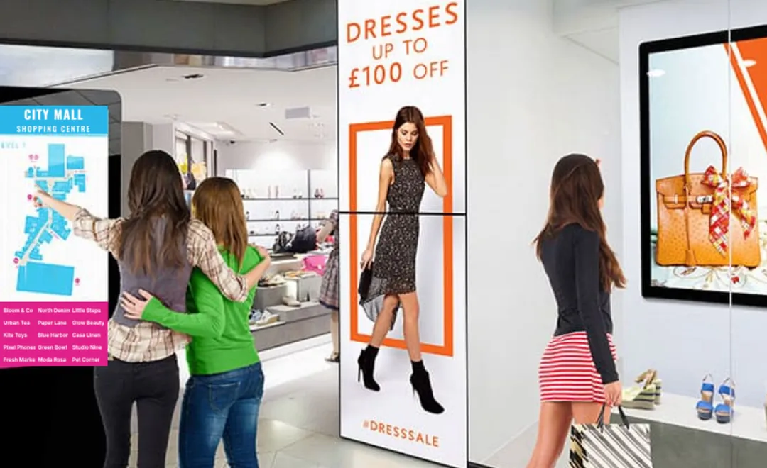Shoppers at a mall directory kiosk beside fashion screens.